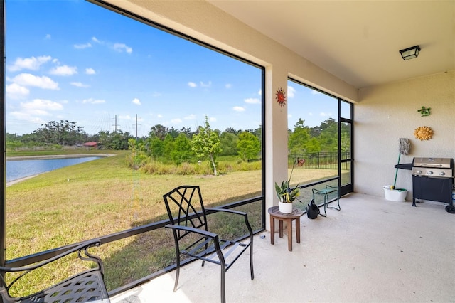 sunroom / solarium with a water view and view of wooded area