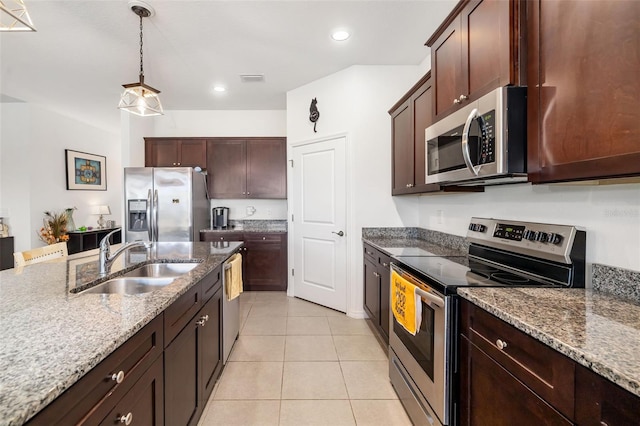 kitchen with appliances with stainless steel finishes, a sink, light stone countertops, light tile patterned flooring, and hanging light fixtures