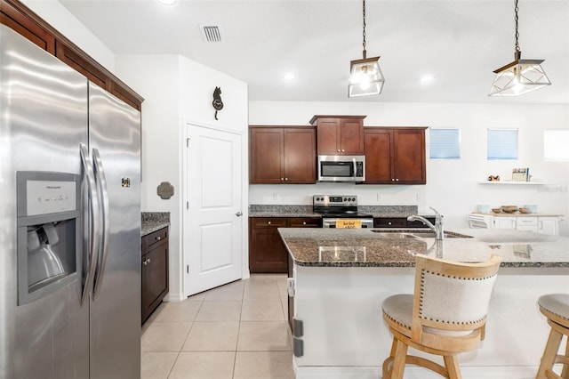 kitchen with stainless steel appliances, a sink, hanging light fixtures, dark stone counters, and recessed lighting