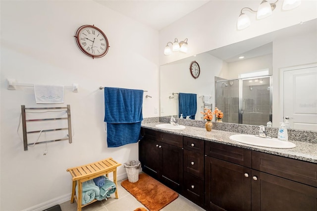 full bathroom featuring a stall shower, baseboards, double vanity, and tile patterned floors