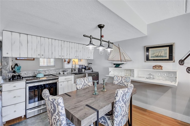 dining space with a textured ceiling, baseboards, and light wood-style floors