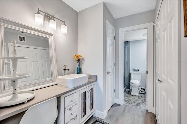 bathroom featuring toilet, wood finished floors, baseboards, and vanity