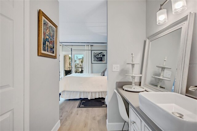 ensuite bathroom featuring wood finished floors, baseboards, and vanity