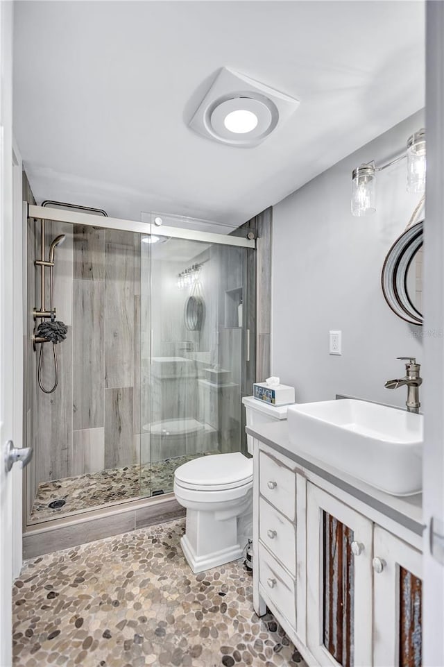 full bath featuring a stall shower, toilet, and vanity