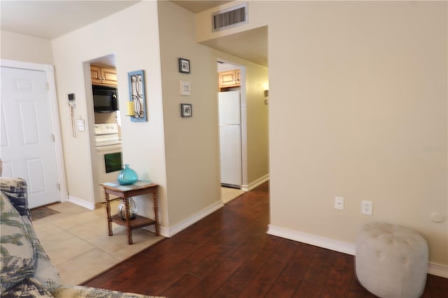 hallway featuring wood finished floors, visible vents, and baseboards