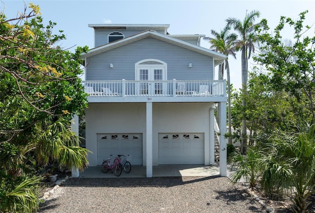 rear view of property featuring a balcony, a garage, and gravel driveway