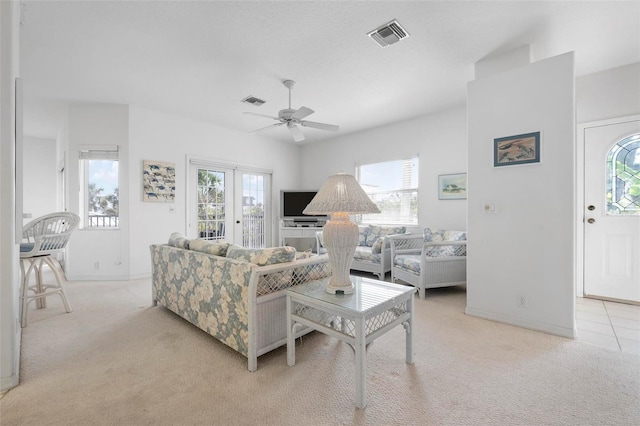 living room with light carpet, plenty of natural light, ceiling fan, and baseboards