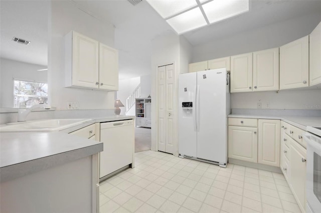 kitchen with white appliances, a sink, light countertops, and white cabinetry
