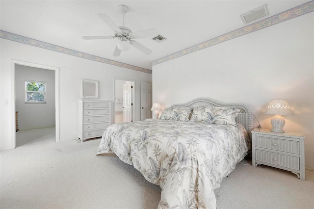 bedroom with light colored carpet, ceiling fan, and ensuite bathroom
