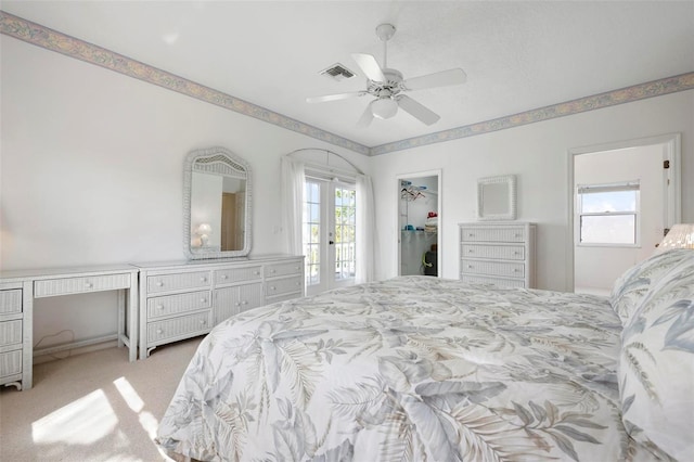 bedroom with carpet, a ceiling fan, a desk, a spacious closet, and french doors