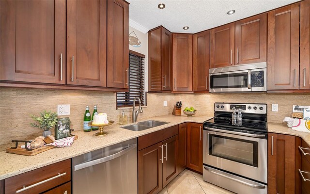 kitchen with stainless steel appliances, light stone counters, tasteful backsplash, and a sink