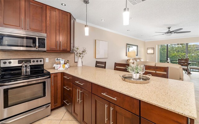 kitchen featuring a peninsula, ornamental molding, light tile patterned flooring, light stone counters, and appliances with stainless steel finishes