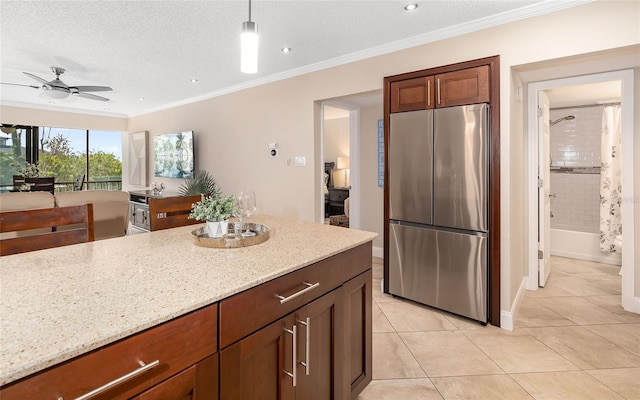 kitchen featuring light tile patterned floors, a ceiling fan, freestanding refrigerator, a textured ceiling, and light stone counters