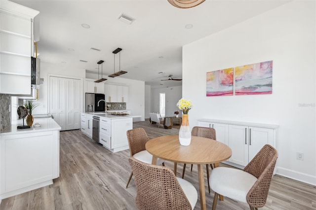 8622 Inwood Dr, Hudson, FL 34667 - dining room featuring light wood finished floors, visible vents, baseboards, and ceiling fan