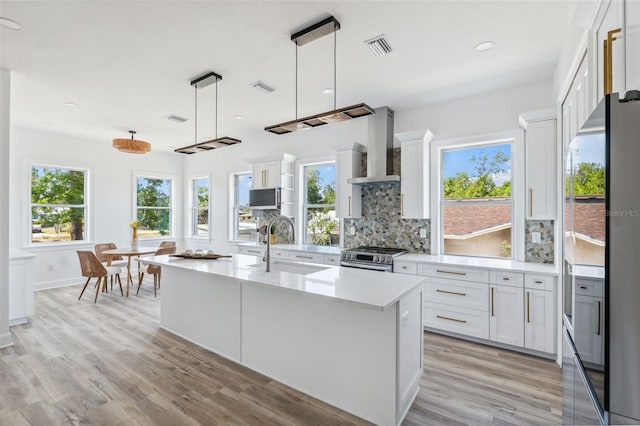 8622 Inwood Dr, Hudson, FL 34667 - kitchen featuring a sink, stainless steel appliances, light wood-type flooring, wall chimney range hood, and decorative backsplash