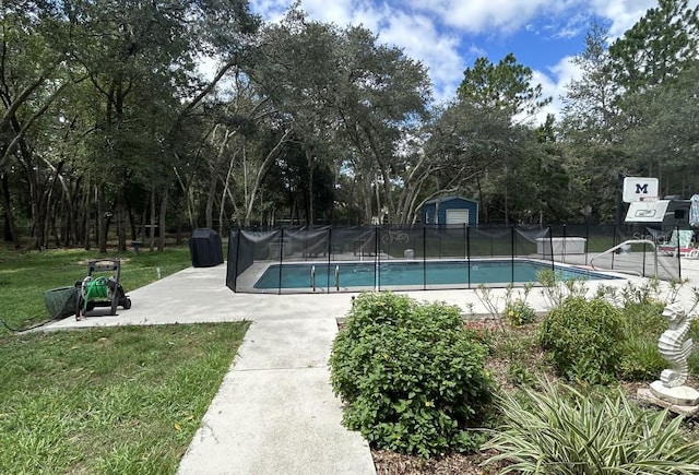 view of swimming pool featuring fence, a lawn, a shed, a patio area, and a fenced in pool