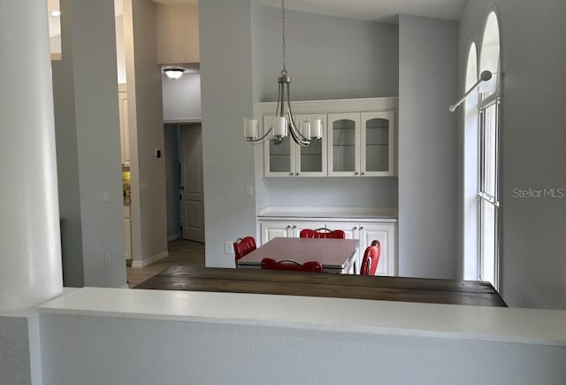 kitchen featuring pendant lighting, glass insert cabinets, baseboards, an inviting chandelier, and white cabinetry