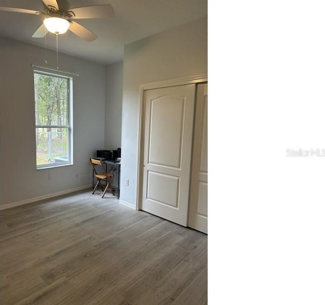 empty room featuring wood finished floors, baseboards, and ceiling fan