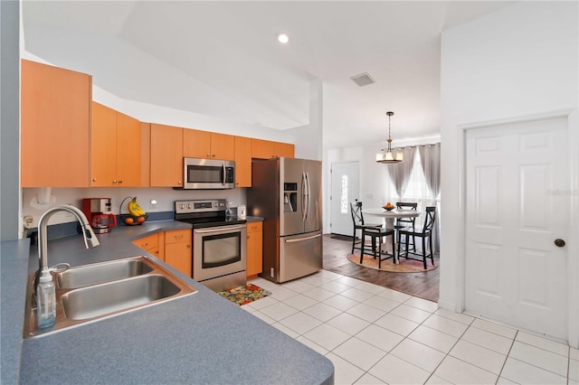 kitchen featuring appliances with stainless steel finishes, a sink, light tile patterned floors, pendant lighting, and dark countertops