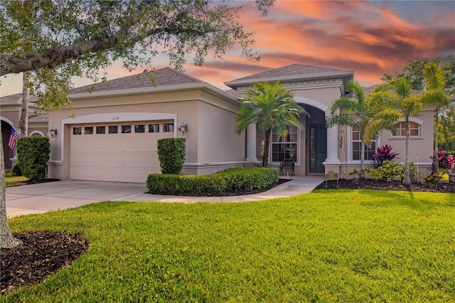 mediterranean / spanish home featuring a lawn, concrete driveway, an attached garage, and stucco siding