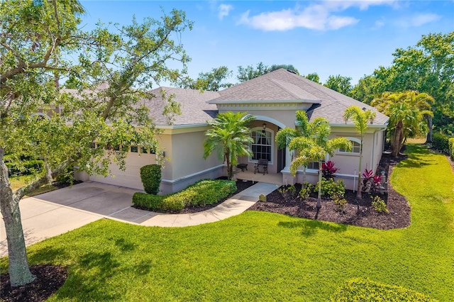 mediterranean / spanish house with stucco siding, a front yard, concrete driveway, a shingled roof, and covered porch