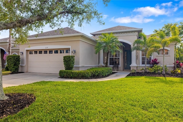 mediterranean / spanish home with a front yard, a garage, concrete driveway, and stucco siding