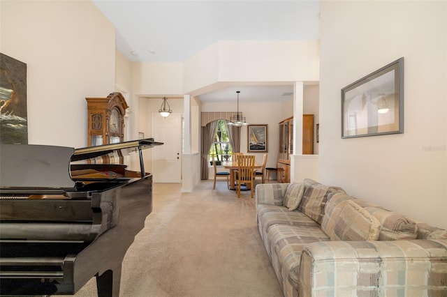 living area featuring light colored carpet, a chandelier, and a high ceiling