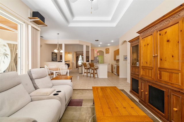 living room with a ceiling fan, light tile patterned flooring, recessed lighting, and a tray ceiling