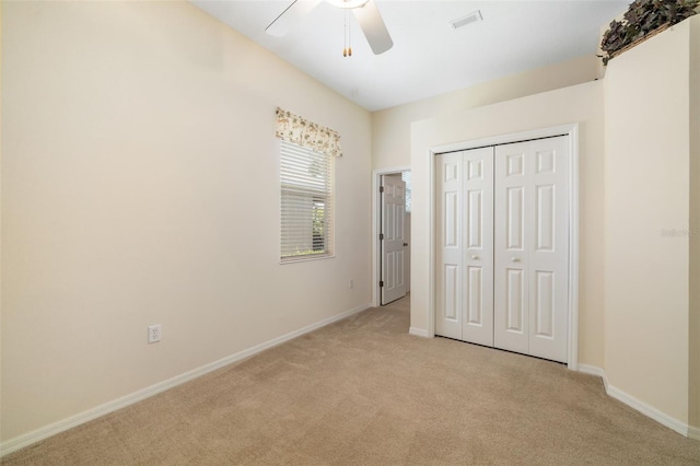 unfurnished bedroom featuring light carpet, a closet, baseboards, and a ceiling fan