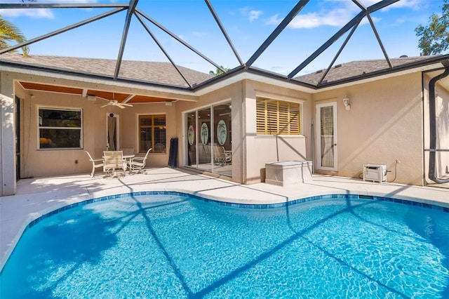 rear view of house featuring stucco siding, a patio, a ceiling fan, an outdoor pool, and a shingled roof