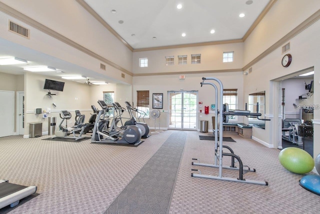 exercise room featuring carpet floors, a high ceiling, crown molding, a ceiling fan, and baseboards