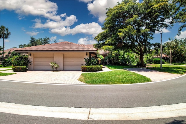 4812 Kestral Park Cir Unit 20, Sarasota, FL 34231 - view of front of home with an attached garage, a tile roof, stucco siding, a front yard, and decorative driveway