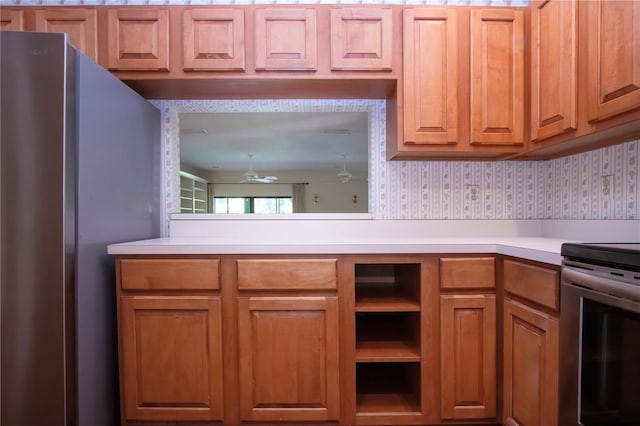 4812 Kestral Park Cir Unit 20, Sarasota, FL 34231 - kitchen featuring a ceiling fan, wallpapered walls, brown cabinetry, light countertops, and appliances with stainless steel finishes