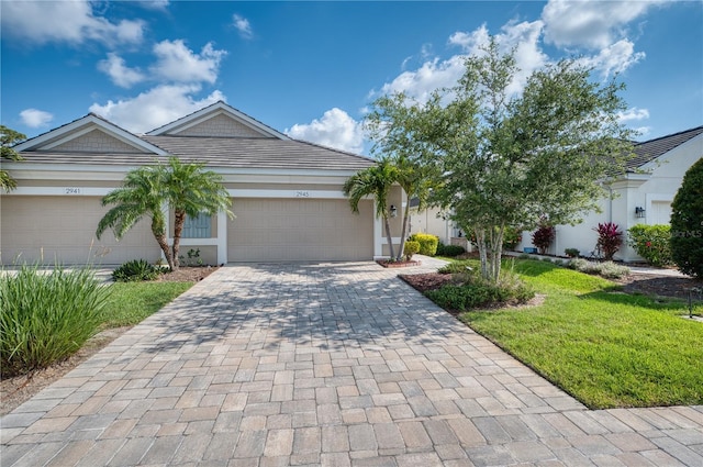 2945 Trustee Ave, Sarasota, FL 34243 - ranch-style home with decorative driveway, an attached garage, a front lawn, and stucco siding