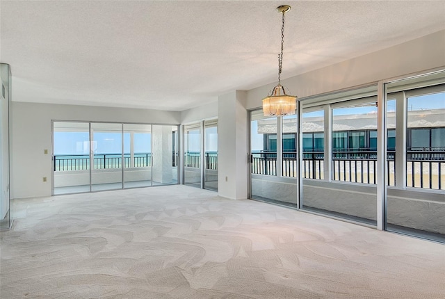 20 Whispering Sands Dr Unit 1201, Sarasota, FL 34242 - carpeted empty room featuring a chandelier, a textured ceiling, and plenty of natural light