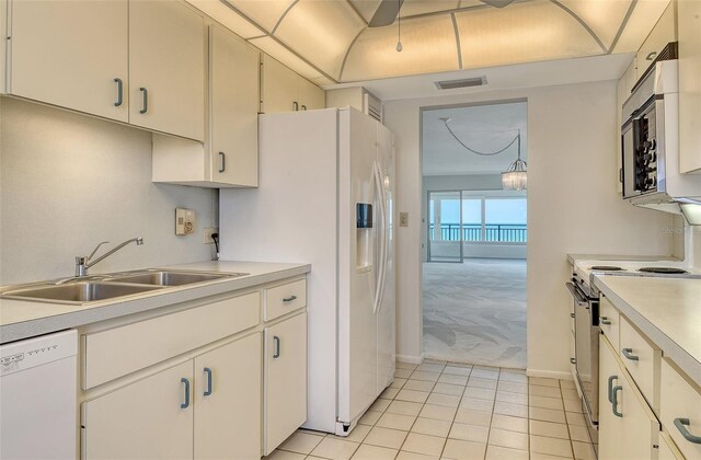 20 Whispering Sands Dr Unit 1201, Sarasota, FL 34242 - kitchen with white appliances, light colored carpet, a sink, light countertops, and light tile patterned floors