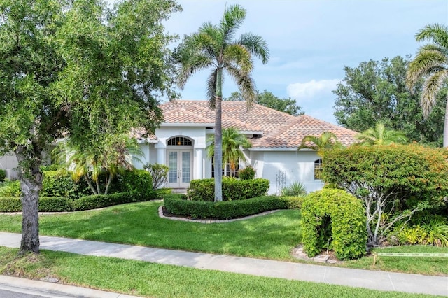 1311 Tuscany Blvd, Venice, FL 34292 - mediterranean / spanish home with french doors, a front lawn, and stucco siding