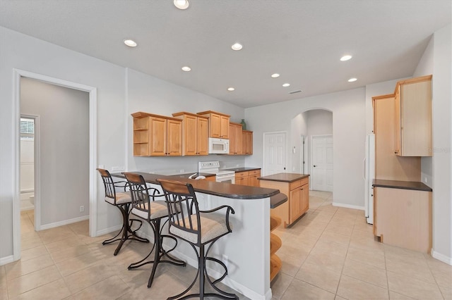 1311 Tuscany Blvd, Venice, FL 34292 - kitchen featuring white appliances, dark countertops, a kitchen island, arched walkways, and open shelves