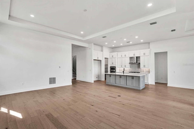 17927 Palmiste Dr, Bradenton, FL 34202 - unfurnished living room featuring a raised ceiling, baseboards, light wood-style floors, stairway, and recessed lighting