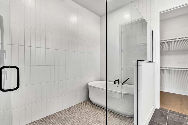 17927 Palmiste Dr, Bradenton, FL 34202 - bathroom featuring tile walls, a shower stall, a spacious closet, a freestanding bath, and tile patterned flooring