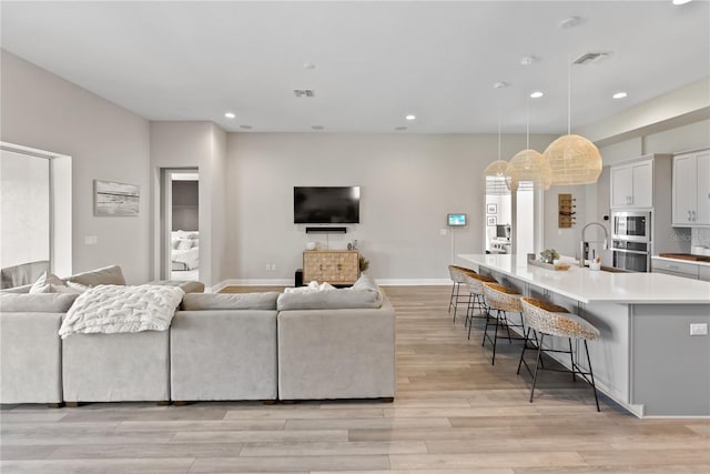living room with light wood-style floors, visible vents, and recessed lighting