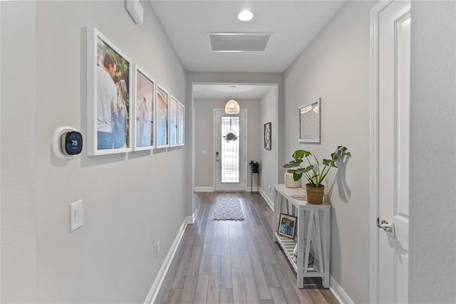 doorway with baseboards, visible vents, and wood finished floors