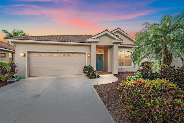 view of front of home featuring concrete driveway, stucco siding, a tiled roof, and a garage