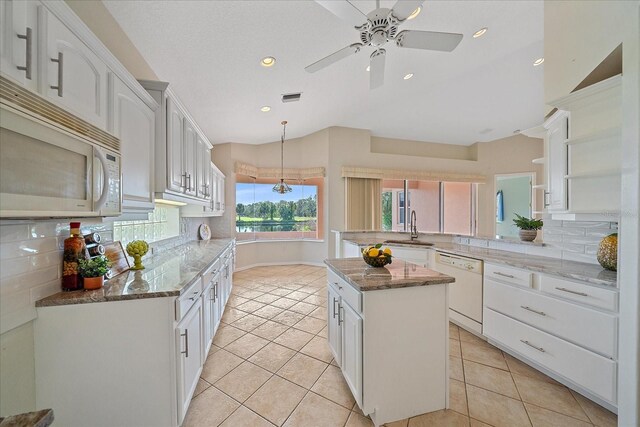 kitchen with white appliances, a sink, white cabinetry, a peninsula, and decorative backsplash