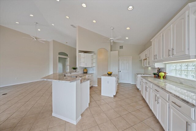 kitchen with open shelves, a peninsula, a ceiling fan, and backsplash
