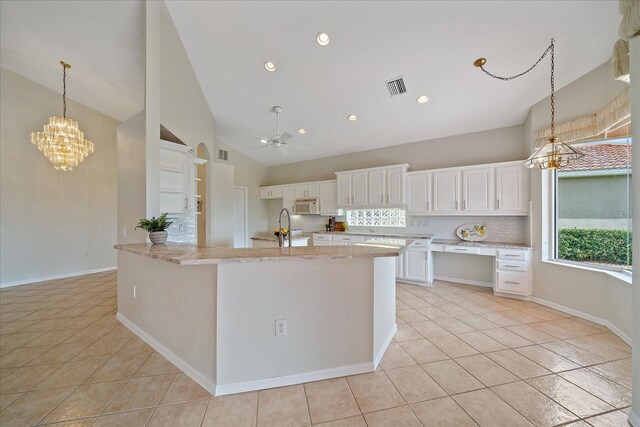 kitchen featuring light tile patterned floors, high vaulted ceiling, white cabinets, visible vents, and white microwave