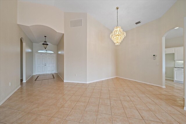 spare room with arched walkways, light tile patterned floors, and visible vents