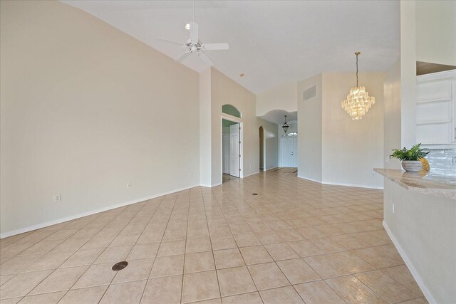 unfurnished room featuring ceiling fan with notable chandelier, high vaulted ceiling, visible vents, arched walkways, and light tile patterned floors