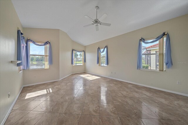 empty room featuring lofted ceiling, baseboards, and ceiling fan