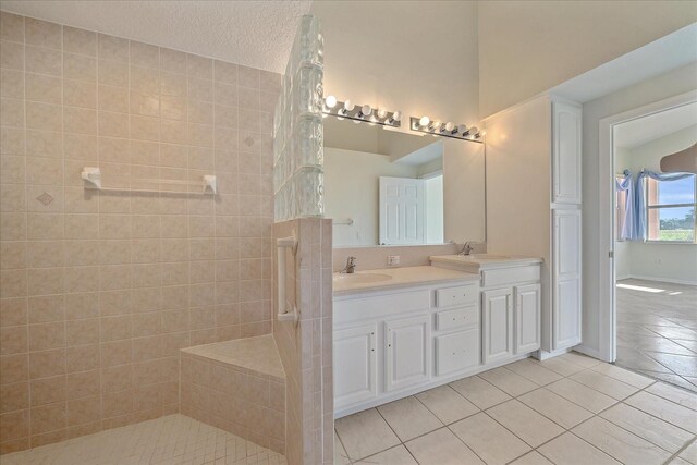 full bath with tile patterned flooring, double vanity, a sink, and a walk in shower